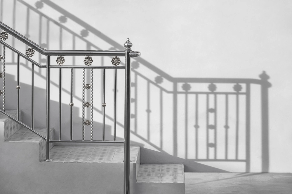 Schody zewnętrzne z betonowymi stopniami i kutą metalową balustradą